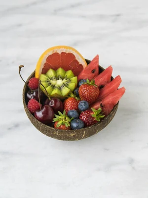 Meio coco servindo de tigela para kiwi, morango, toranja e melancia